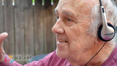 elderly man wearing headphones and smiling while listening to music