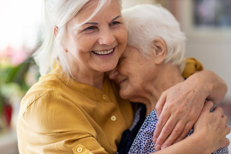 A mother and daughter hugging and smiling