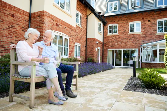 couple sitting outside of assisted living community laughing
