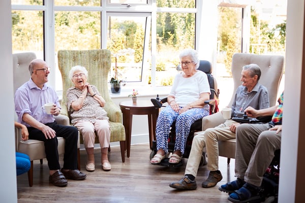 group of seniors sitting around laughing and talking in a sunny room