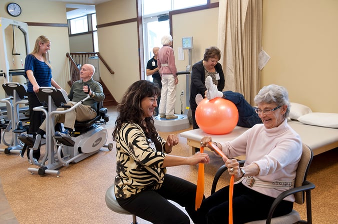 Walker Methodist rehab staff work with room of eldery residents 